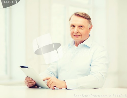 Image of old man with tablet computer at home