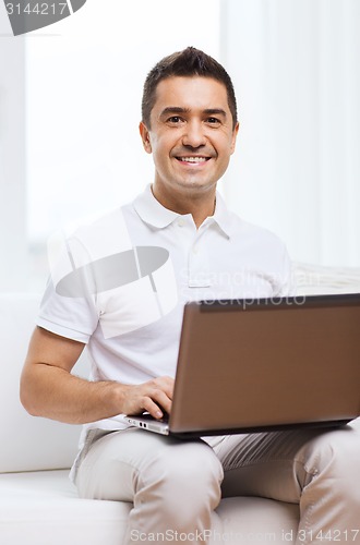 Image of happy man working with laptop computer at home