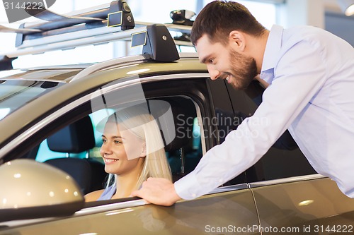 Image of happy couple buying car in auto show or salon