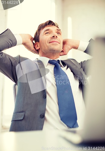 Image of relaxed businessman with laptop in office