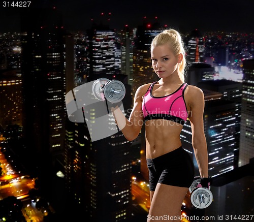 Image of sporty woman with heavy steel dumbbells