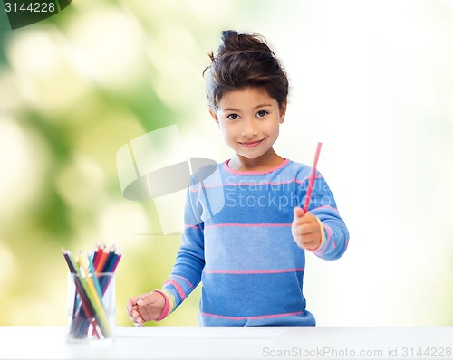 Image of happy little girl drawing with coloring pencils