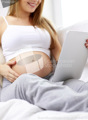 Image of close up of pregnant woman with tablet pc at home