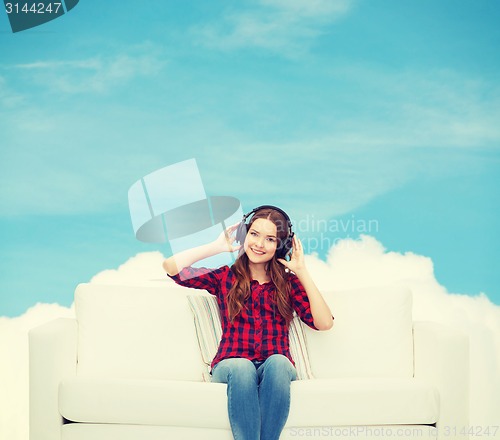 Image of teenage girl sitting on sofa with headphones