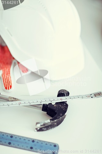 Image of blueprint, flexible ruller, helmet and hammer