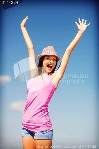 Image of girl with hands up on the beach