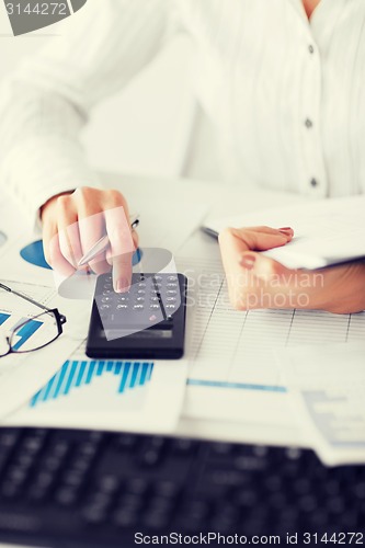 Image of woman hand with calculator and papers