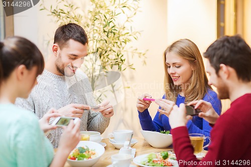 Image of friends with smartphones taking picture of food