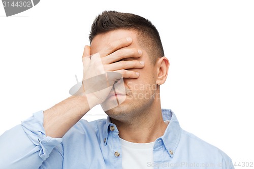 Image of unhappy man covering his eyes by hand
