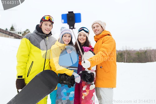 Image of happy friends with snowboards and smartphone