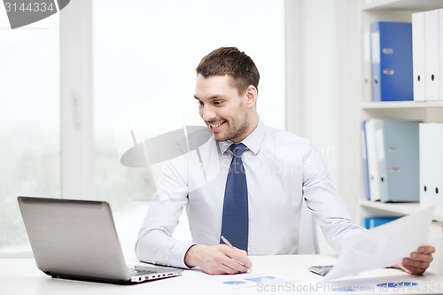 Image of smiling businessman with laptop and documents