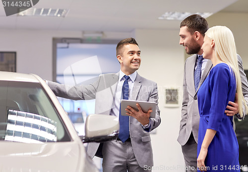 Image of happy couple with car dealer in auto show or salon