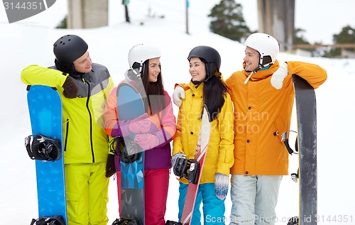 Image of happy friends in helmets with snowboards talking