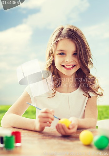 Image of smiling little girl coloring eggs for easter