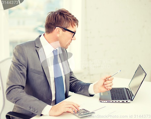 Image of businessman with computer, papers and calculator