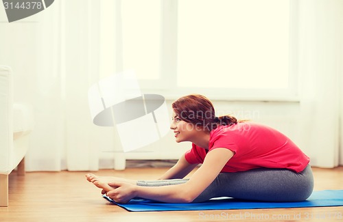 Image of smiling teenage girl streching on floor at home