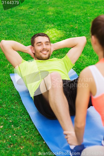 Image of smiling man doing exercises on mat outdoors