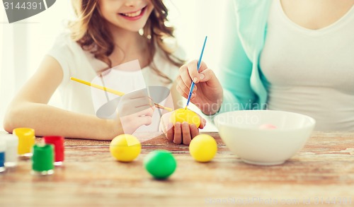 Image of close up of little girl and mother coloring eggs