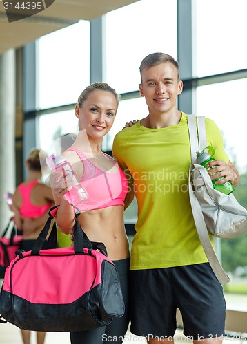 Image of smiling couple with water bottles in gym