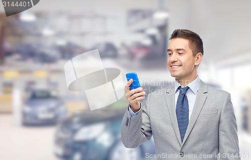 Image of happy businessman texting on smartphone