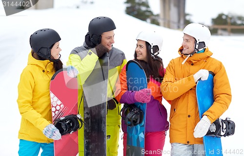 Image of happy friends in helmets with snowboards talking