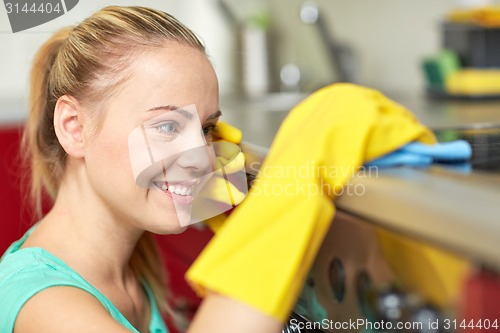 Image of happy woman cleaning cooker at home kitchen