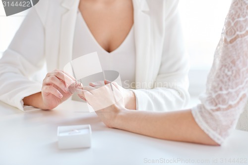 Image of close up of lesbian couple hands with wedding ring