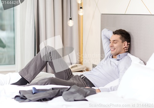 Image of happy businesswoman lying in bed in hotel room