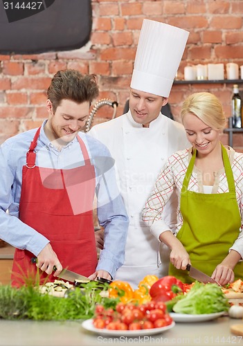 Image of happy couple and male chef cook cooking in kitchen