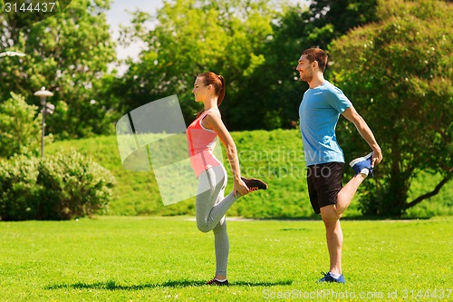 Image of smiling couple stretching outdoors