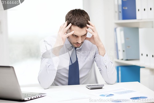 Image of stressed businessman with laptop and documents