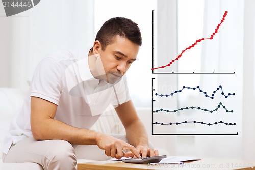 Image of man with papers and calculator at home