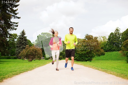 Image of smiling couple running outdoors