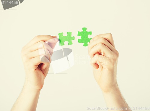 Image of two hands trying to connect puzzle pieces