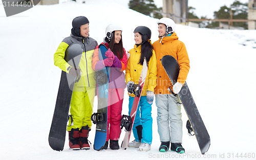 Image of happy friends in helmets with snowboards talking