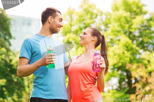 Image of smiling couple with bottles of water outdoors