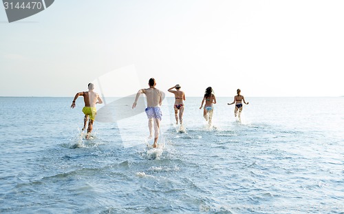 Image of smiling friends running on beach from back