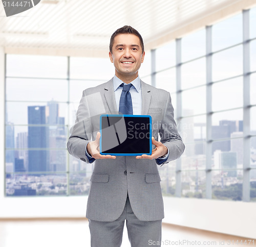 Image of happy businessman in suit showing tablet pc screen