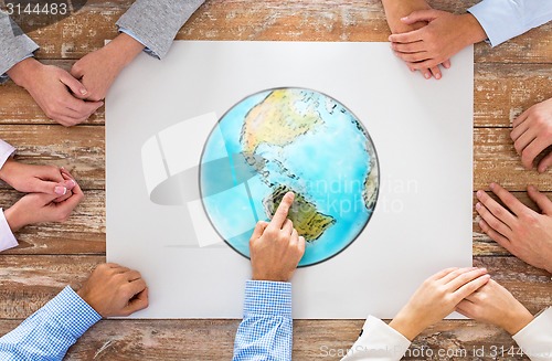 Image of close up of hands with globe picture at table