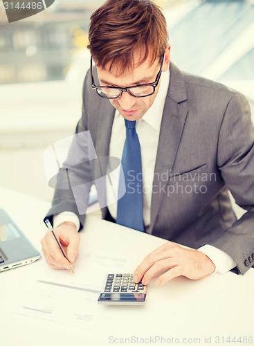 Image of businessman with computer, papers and calculator