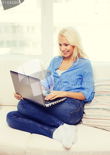 Image of smiling woman with laptop computer at home