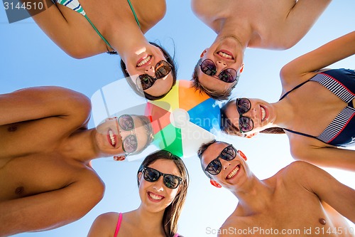 Image of smiling friends in circle on summer beach