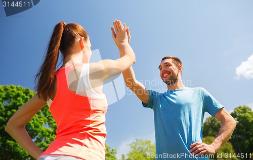 Image of two smiling people making high five outdoors