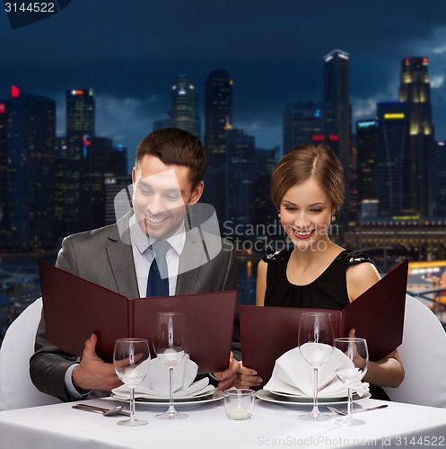 Image of smiling couple with menus at restaurant