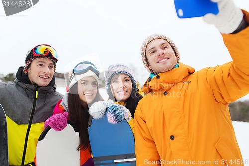 Image of happy friends with snowboards and smartphone