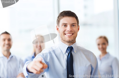 Image of smiling businessman with colleagues in office