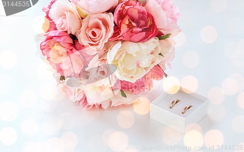 Image of close up of two wedding rings and flower bunch