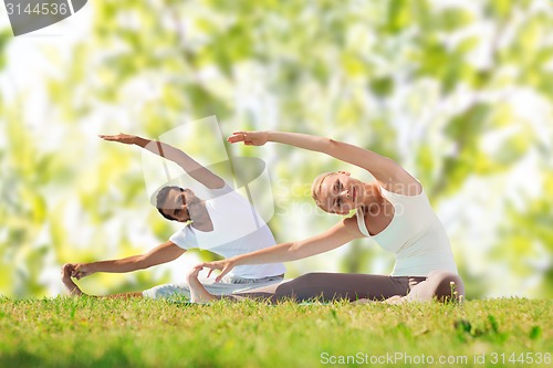 Image of happy couple stretching and doing yoga exercises