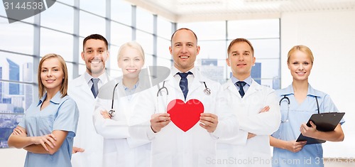 Image of happy young doctors cardiologists with red heart