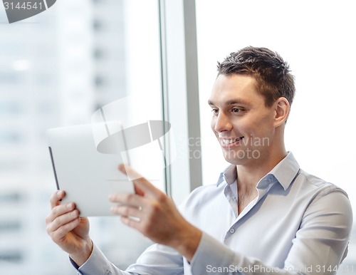 Image of smiling businessman with tablet pc in office